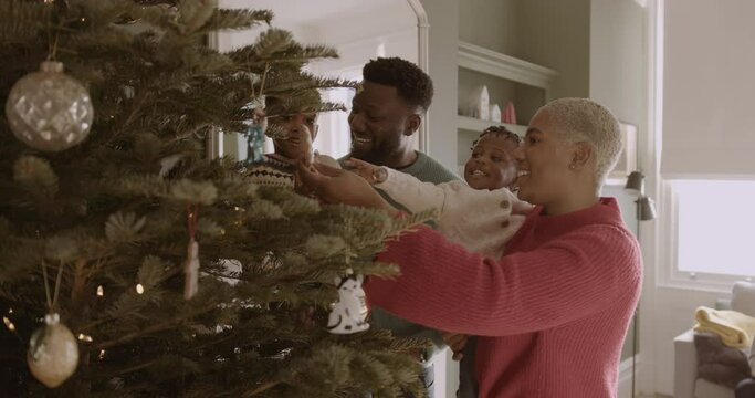 Parents with Daughter Decorating Christmas tree with Multi generational family Celebrating