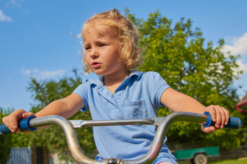 Obraz premium little girl driving a bicycle,a child holds the handlebars of a bicycle at sunset