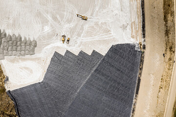 Aerial view of remediation work on a terrain with mining waste fillings, where working machinery...