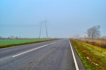 Fototapeta premium Photo of a road with a power line in the fog