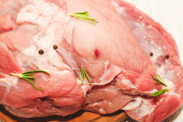 Fresh piece of meat large pork ham on a board with pepper.