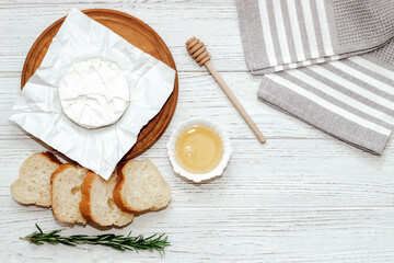Camembert cheese with baguette croutons and a sprig of rosemary with honey on the table.