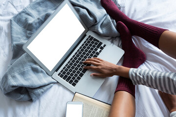 Low section of woman using laptop on bed