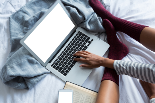 Low section of woman using laptop on bed