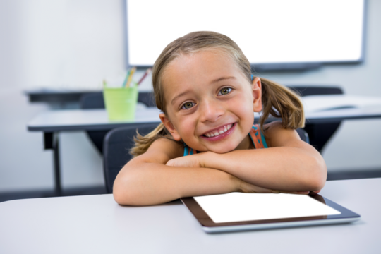 Girl sitting by digital tablet in classroom