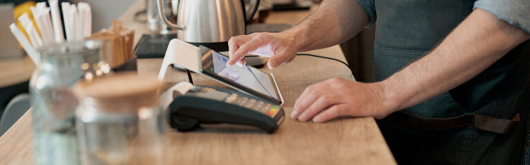 Close up of barista uses a digital tablet to take an order at a coffee shop