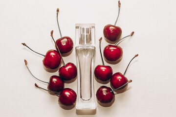 Fototapeta na wymiar Ripe red cherries with perfume bottle on white table.