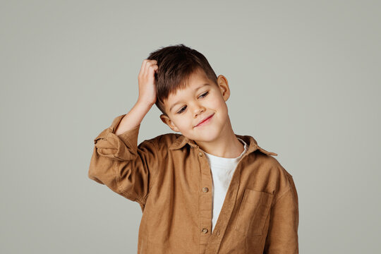 Pensive caucasian 6 years old little kid scratching head with hand thinks, look at empty space