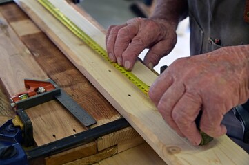 Close up of carpenter hands measuring a wooden plank