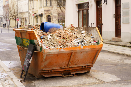 The Yellow Metal Bin Is Filled With Building Debris And Is Ready To Be Collected From The Street