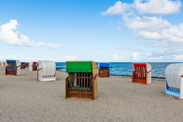 beach chairs in different colors in the sand of a stand by the sea