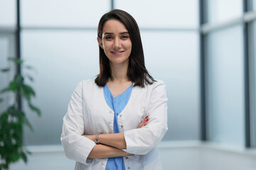 female doctor in lab coat with arms crossed against