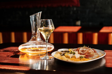 decanter and a glass of white wine. cheese set with  jam, fruit and nuts