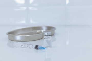 Syringe and glass bottle with metal tray on white background