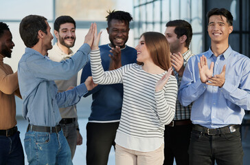 Human resources. Group portrait of smiling employees of a friendly team of different racial genders standing together in an office. © Katsiaryna