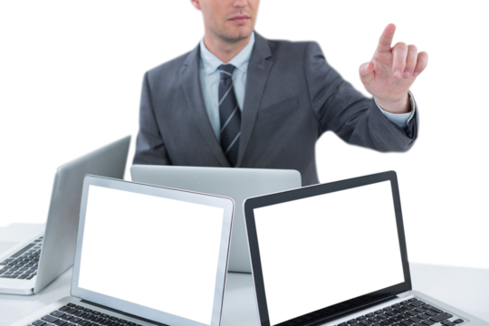 Businessman gesturing while sitting at table with four laptops