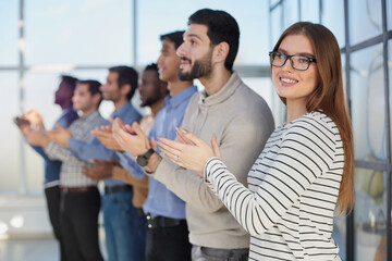 Obraz premium Business people applaud in a conference room standing in a row. Side view