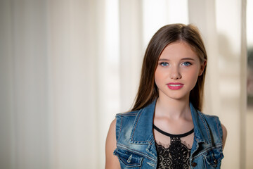 Portrait of a beautiful young brunette woman with blue eyes in a denim vest