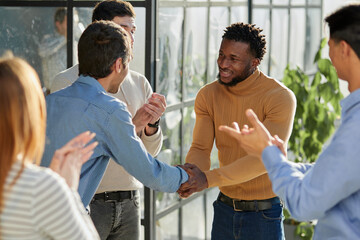 Smiling multiethnic friend getting acquainted in office corridor