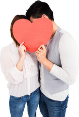 Young couple covering face with heart shape paper