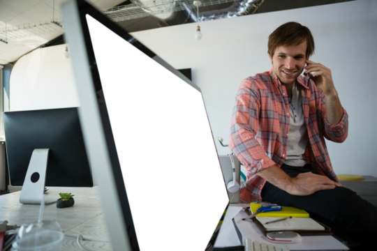 Man talking on mobile phone while looking at computer