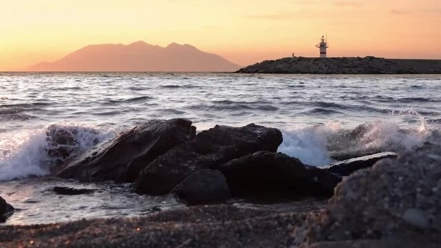 Sunset seascape with Lighthouse  view towards Samothrace Island from Kalekoy harbour G&ouml;k&ccedil;eada. A man walking slowly near the lighthouse.Imbros Canakkale Turkey