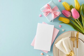 Mother's Day concept. Top view photo of plate with cutlery knife fork fabric napkin postcard gift boxes colorful hearts and yellow pink tulips on isolated pastel blue background with copy space