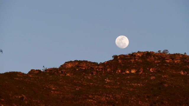 Serene video of full moon rising behind mountains in Vale do Capao, Chapada Diamantina, Bahia, Brazil. Breathtaking scene evokes wonder, tranquility 