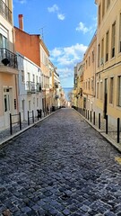 One of the streets of Lisbon that leads down to a large river and the city center