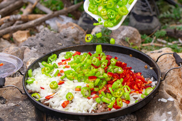 man prepares food on a campfire in a clearing near the mountains. Stalker, survive in the jungle