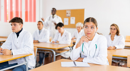 Portrait of doctors different age who writing exercises at lesson in university