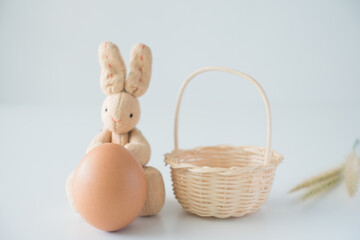 Fototapeta na wymiar Happy easter, Easter bunny or rabbit or hare doll sits with an egg and blurred basket in the background isolated on white background for your decoration in holiday. copy space.
