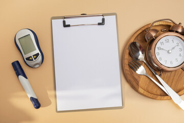 Empty text board and glucometer and cutlery with alarm clock on plate flat lay, top view. Mock up diabetes theme