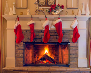 Five red stockings on the stone hearth with a blazing fire for Christmas holidays.