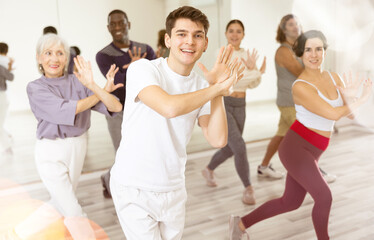 Fototapeta na wymiar Caucasian guy practising dance moves with other people in dance studio