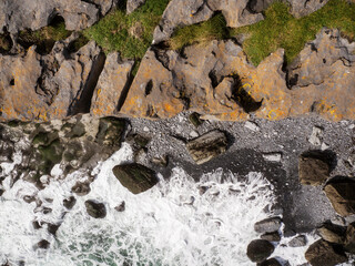 Top down view from top of a cliff on a powerful ocean waves crushing on rough stone coastline of Aran Island, county Galway, Ireland. Irish landscape and nature scene.