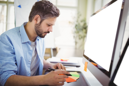 Man working while sitting by computer monitor