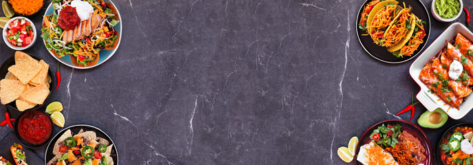 Mexican food double border. Top down view on a dark stone banner background. Tacos, burrito plate, nachos, enchiladas and tortilla salad. Copy space.