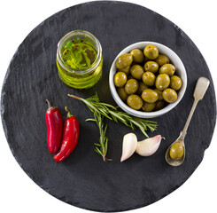 Green olives, herbs, olive oil and red chilies on table