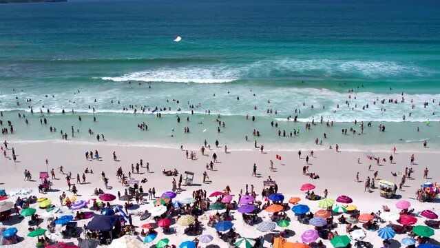 
Vista de drone sobre a praia cheia de turistas e guarda-sol, mar limpo e areia branca na cidade de Cabo Frio, Rio de Janeiro, Brasil
