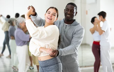 Fotobehang Dansschool African man and caucasian lady rehearsing latin paired dance moves