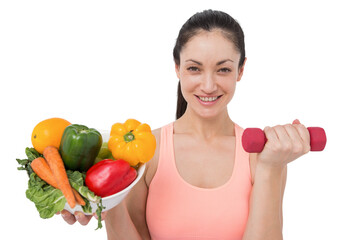 Fit brunette lifting dumbbell and holding bowl of salad - Powered by Adobe
