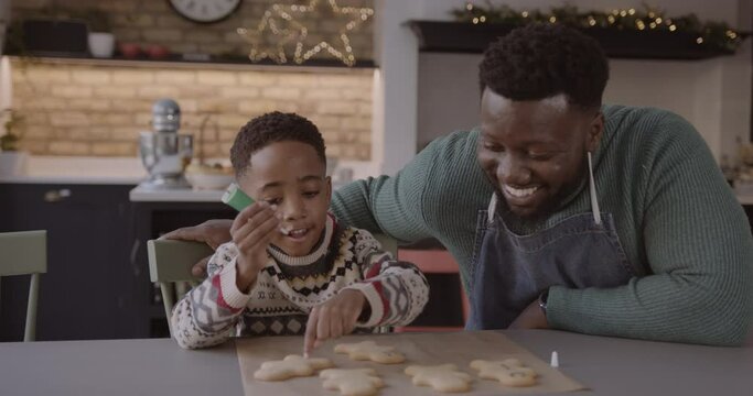 Father and Son Decorating Gingerbread men Together at Christmas