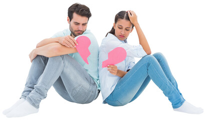 Sad couple sitting holding two halves of broken heart