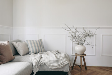 Stylish living room with vase and blooming cherry plum tree branches. Springtime home decor....
