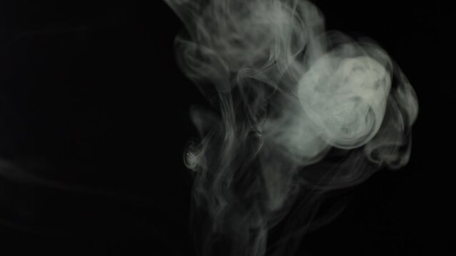 Black background and smoke. Lots of cigarette smoke. Suitable for effects in various videos. It's a pity for the environment. Stop smoking in public places. Thick white smoke on a black background.