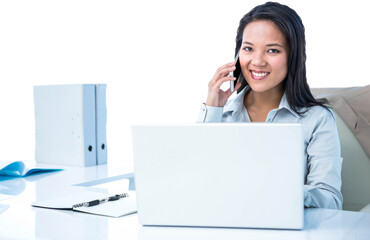 Smiling businesswoman phoning at the desk