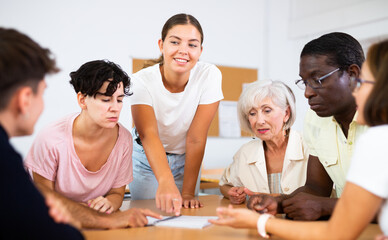 Teacher, together with group of adult students, are looking for solution to complex tasck at round table in a university