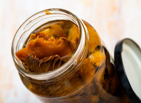 Tasty homemade pickled mushrooms lactarius deliciosus in open jar on table..