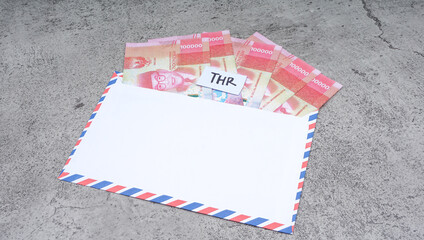 An envelope full of Indonesian rupiah with THR Text.  THR is holiday allowance on Eid al-Fitr or Lebaran days.
